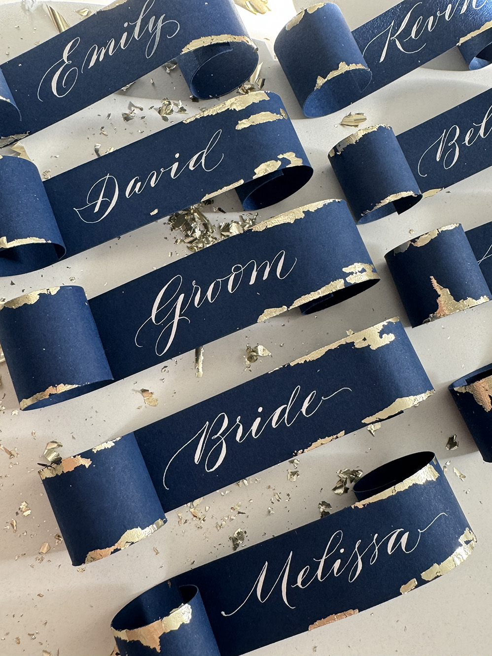 Place cards. Guest names on a blue background framed in gold.