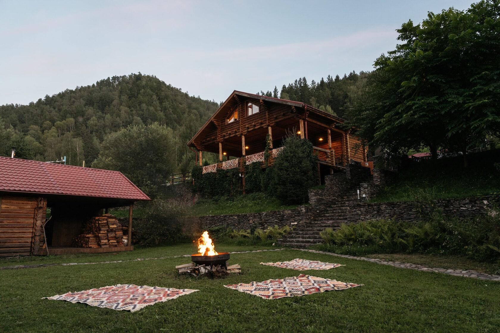 Evening bonfire with kilims on lawn near chalets