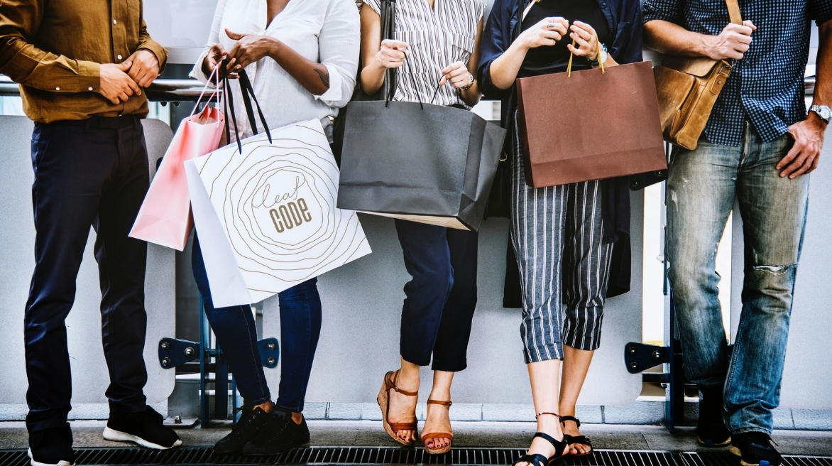 Покупатели с фирменными пакетами Leaf Code: Группа людей с фирменными пакетами Leaf Code, представляющая разнообразие клиентской базы.