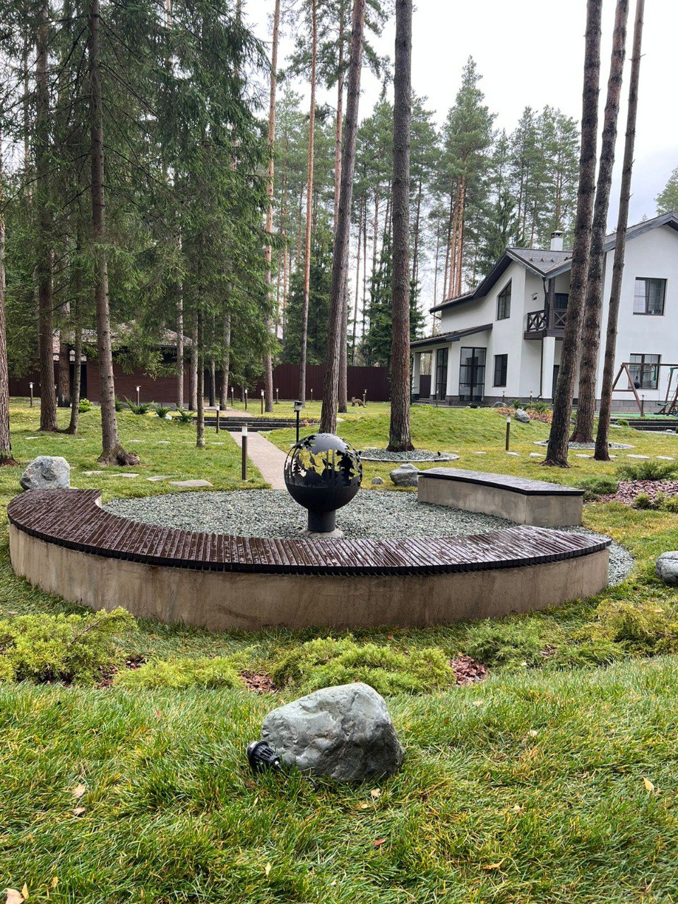 Сравнение сада у дома сегодня и через 10 лет: слева — молодой участок с небольшой растительностью и прямой дорожкой, справа — зрелый сад с большими деревьями, извилистой тропинкой, цветущими кустарниками и перголой с лавочкой.