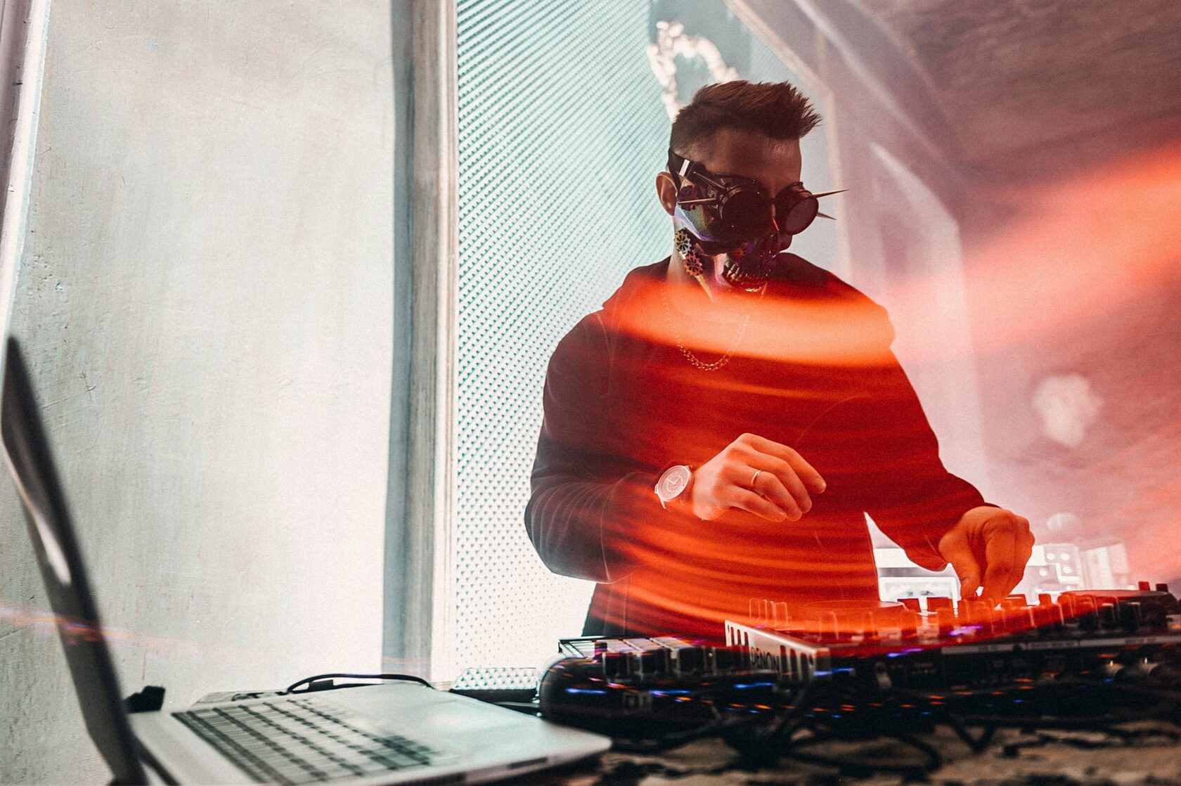 DJ ROZHKOV работает за пультом на сцене со световыми следами оранжевого цвета в кадре.