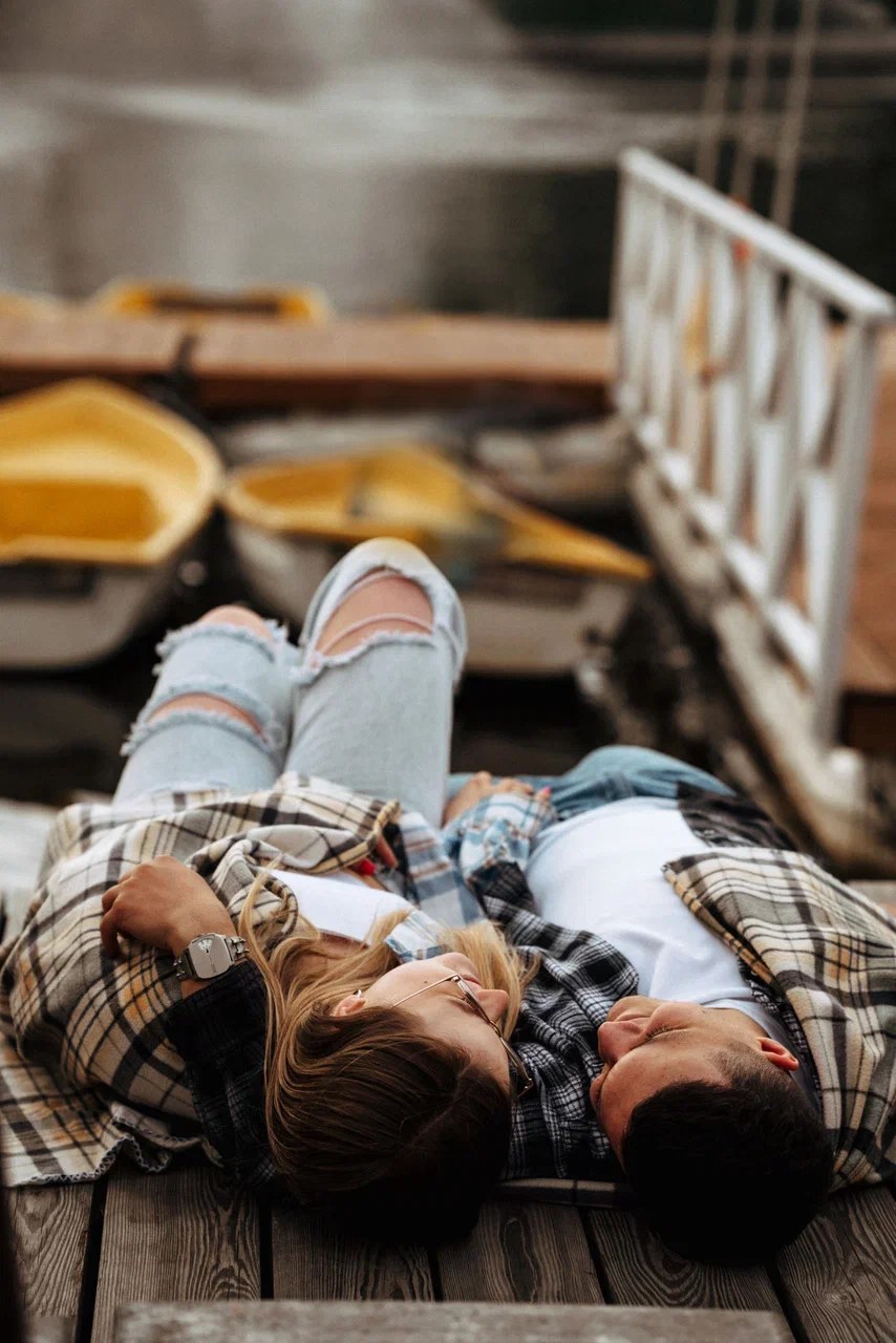 Пара лежит рядом на деревянном настиле во время фотосессии Love Story на прогулке