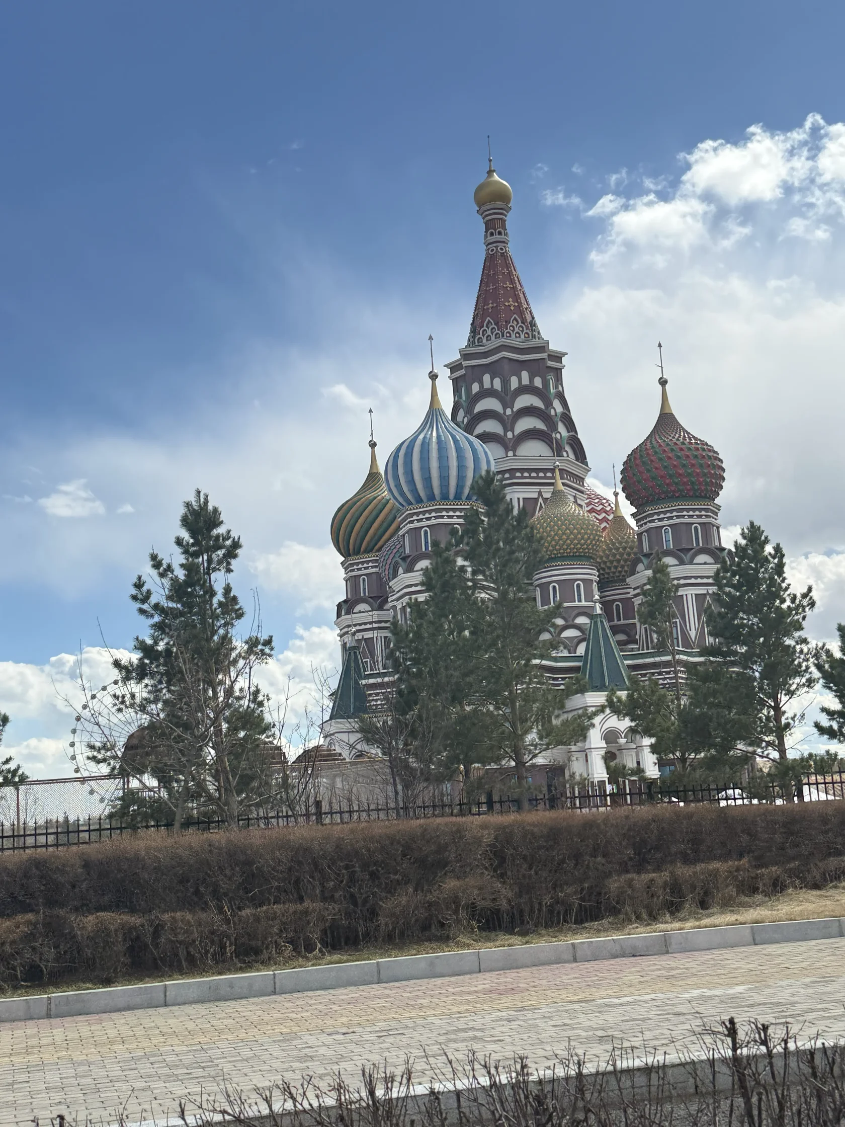 Декоративное здание с разноцветными куполами за деревьями