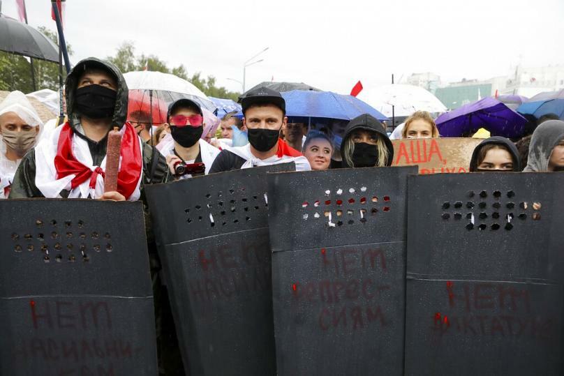 Protesters hold shields painted with the words 'No Repression' facing a police line in Minsk, September 2020