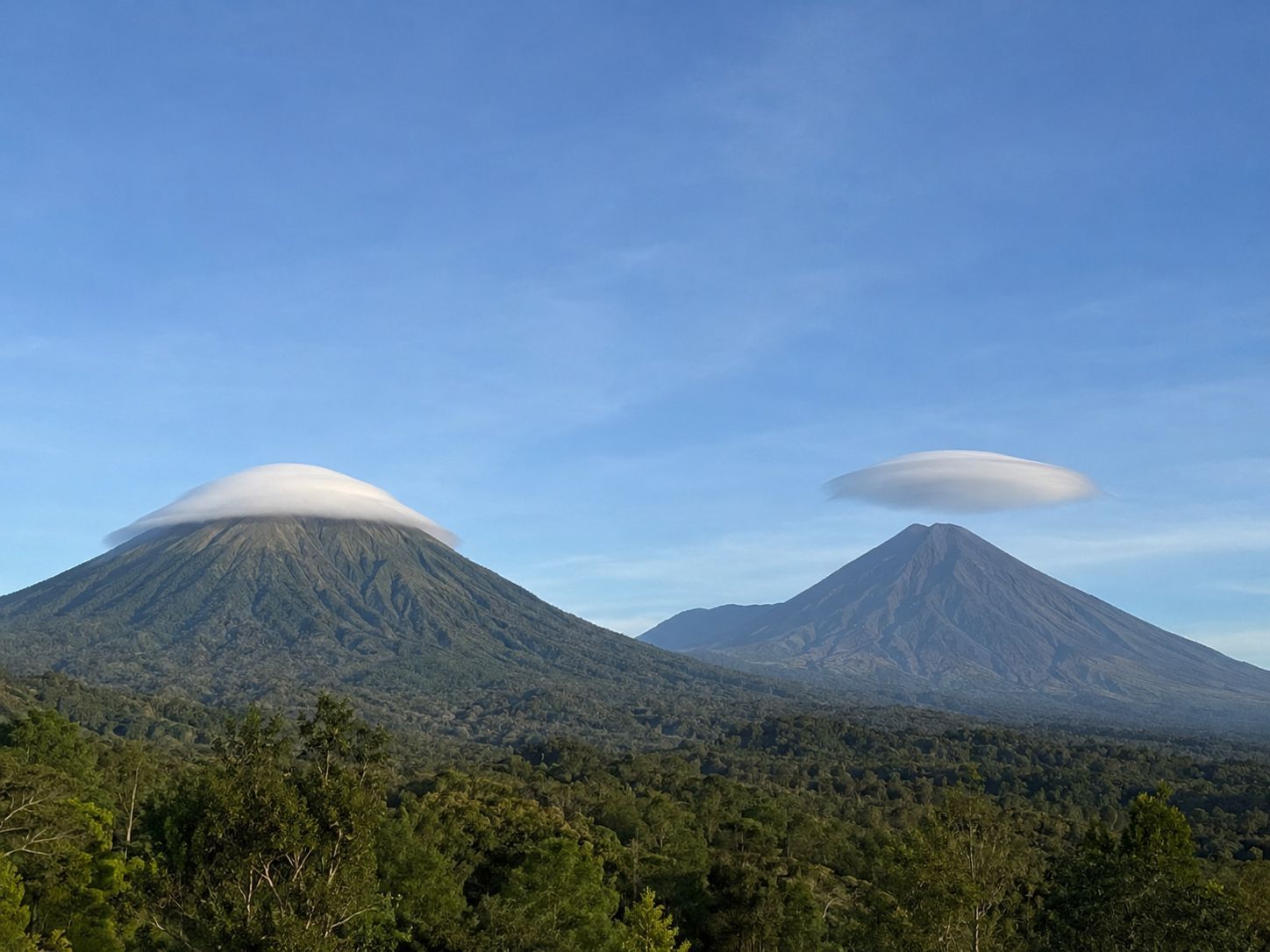 Awan topi membungkus puncak gunung dan awan lentikular berbentuk lensa di dekatnya