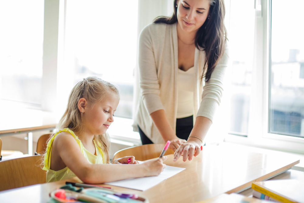 A teacher helping a schoolgirl with AI technology in a modern classroom