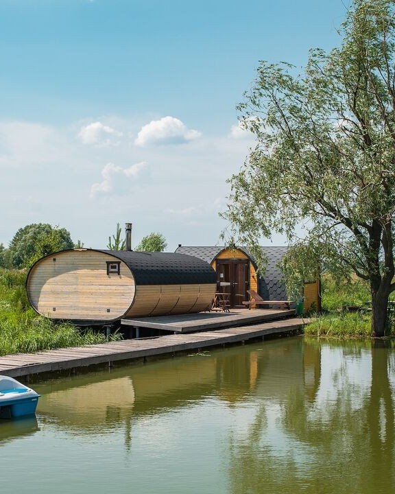 The large wood-fired Russian banya on its deck at the water, with the bungalow behind