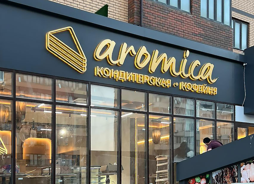Объемные буквы из черного глянцевого акрила с алюминиевыми бортами и контражурной подсветкой на фоне серебристого композита. В светлое время - стильно и серьёзно. В темное время суток - яркий контур вокруг букв!