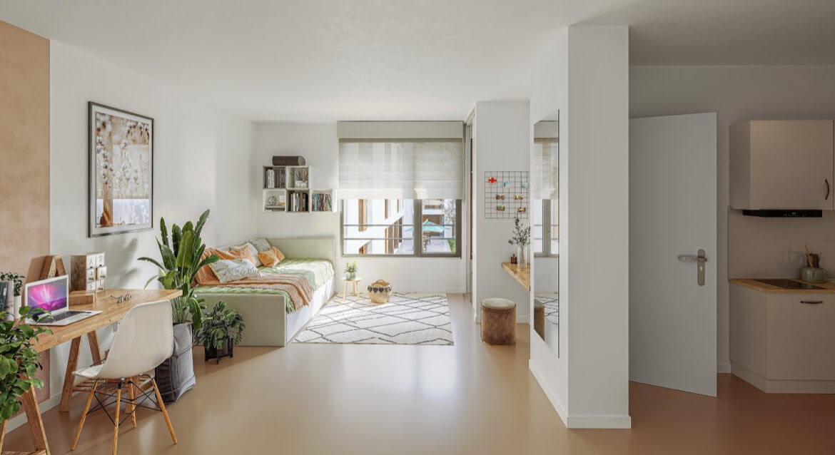 A cozy, bright studio apartment in Scandinavian style, featuring a sleeping area, a wooden desk with a laptop, and a compact kitchenette. The light-toned interior is enhanced with natural elements and green plants. A large window with Roman shades illumin