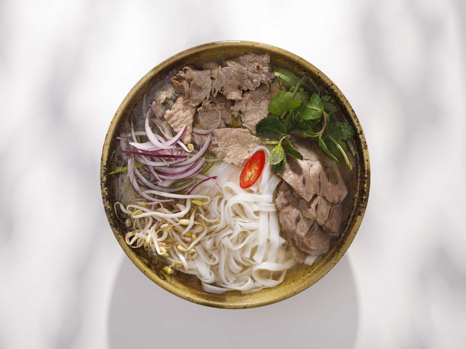Фо бо с говядиной, рисовой лапшой, ростками и зеленью в PhoBo.