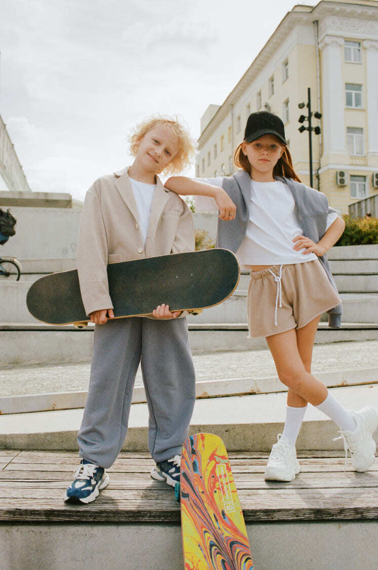 девочка в бежевых шортах, белой футболке и сером худи