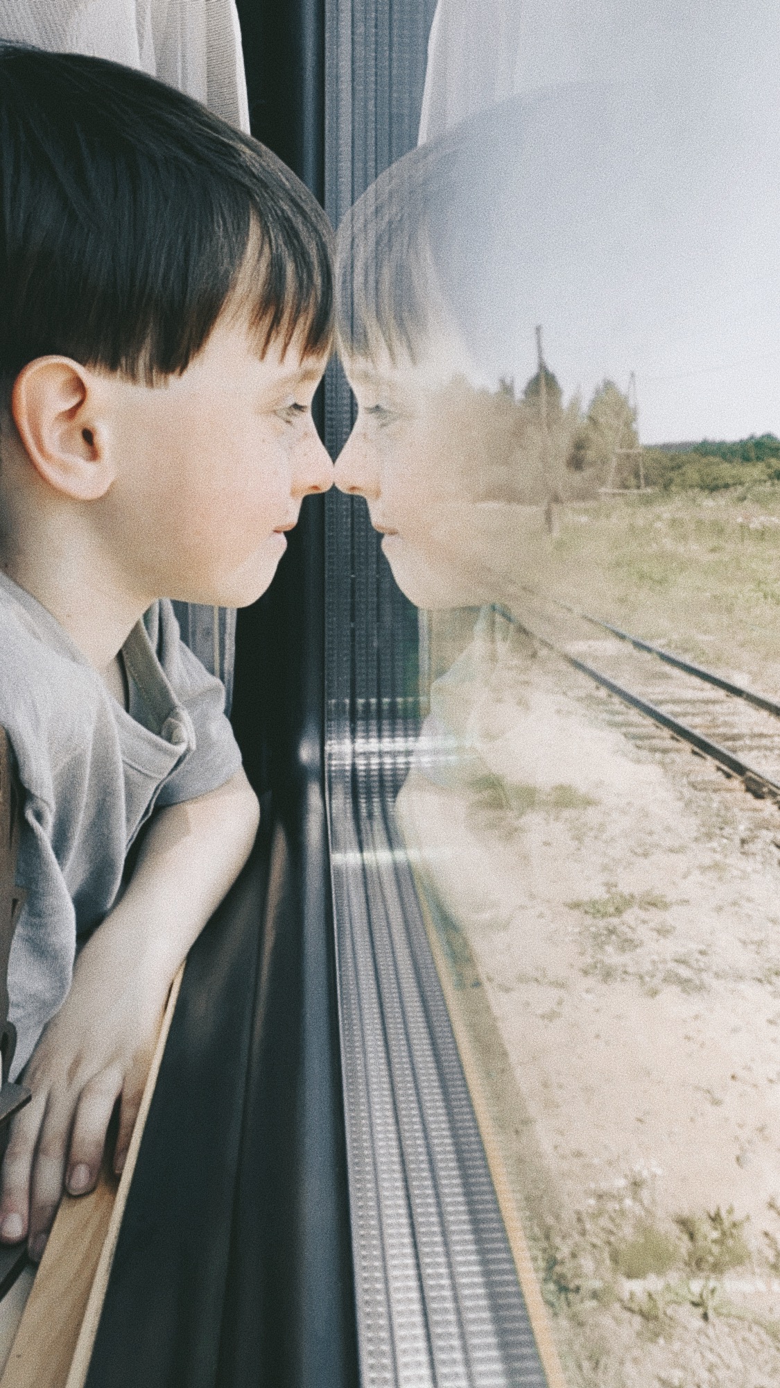 мальчик смотрит в окно в поезде