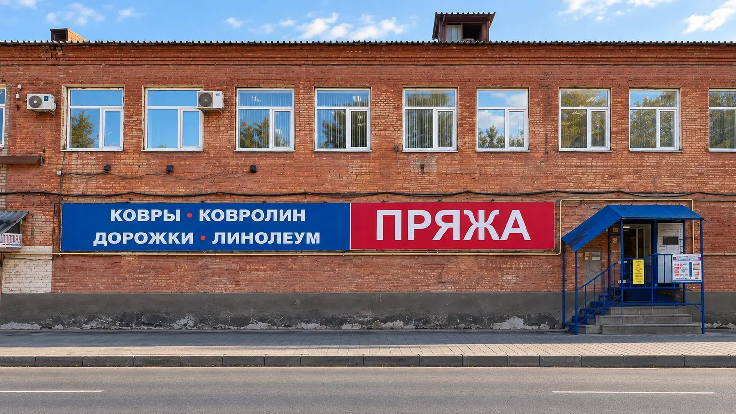 Кирпичное здание с баннерами Ковры Ковролин Дорожки Линолеум и Пряжа, вход по синему крыльцу