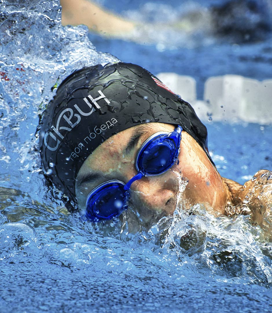 Крупное лицо пловца в бассейне, фирменная резиновая шапка с логотипом