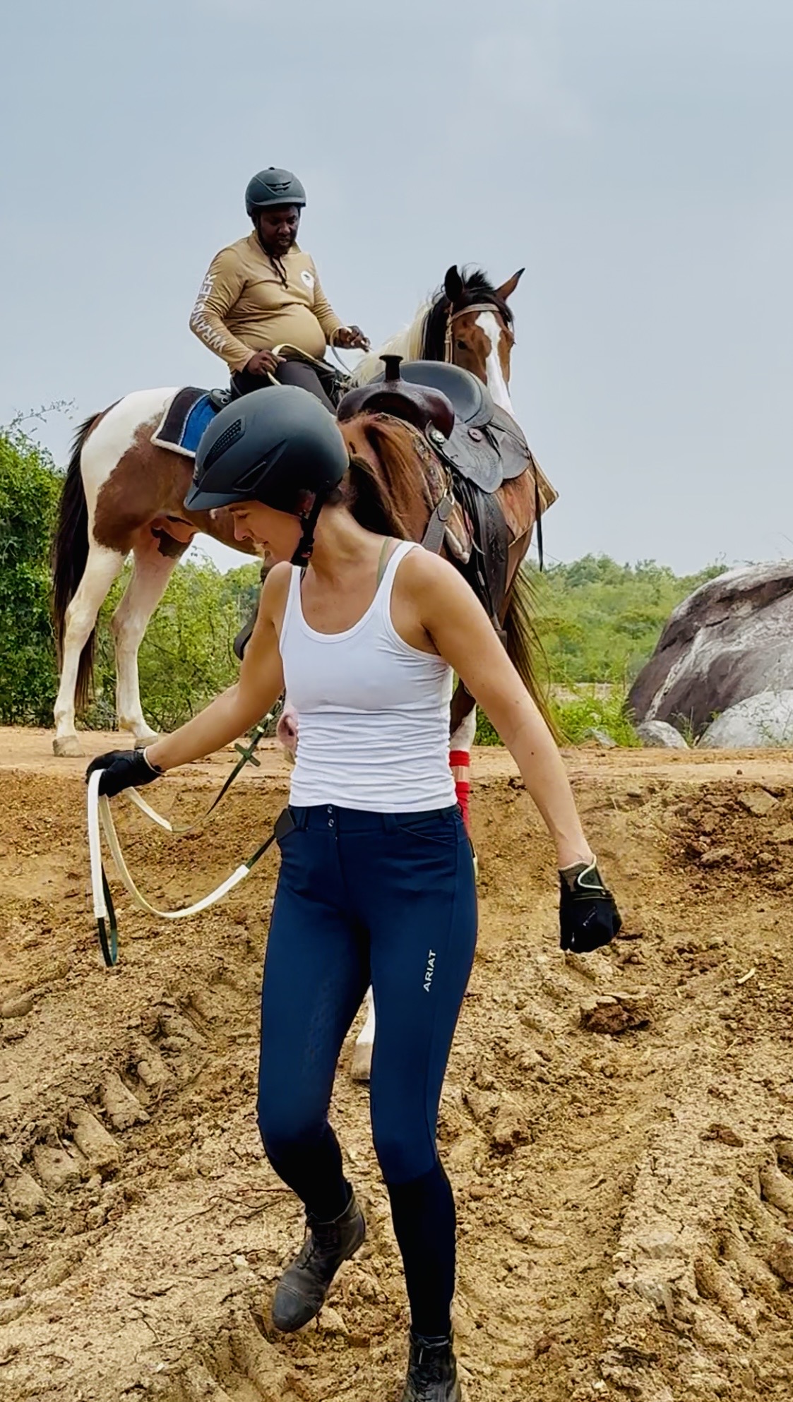 Horseback rider at Vonfidel Ranch walking beside a saddled horse through dry tropical terrain in Sri Lanka, reflecting the Ranch’s calm, low-volume and welfare-first riding philosophy.