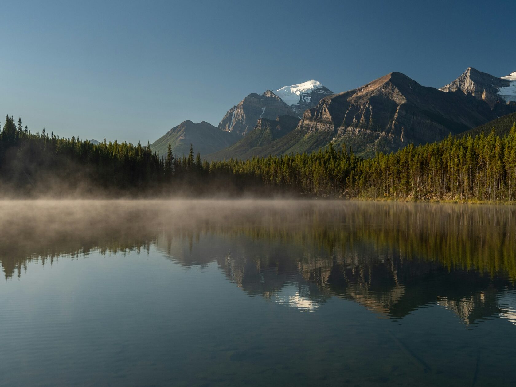 Misty mountain lake with still water and dramatic peak reflection