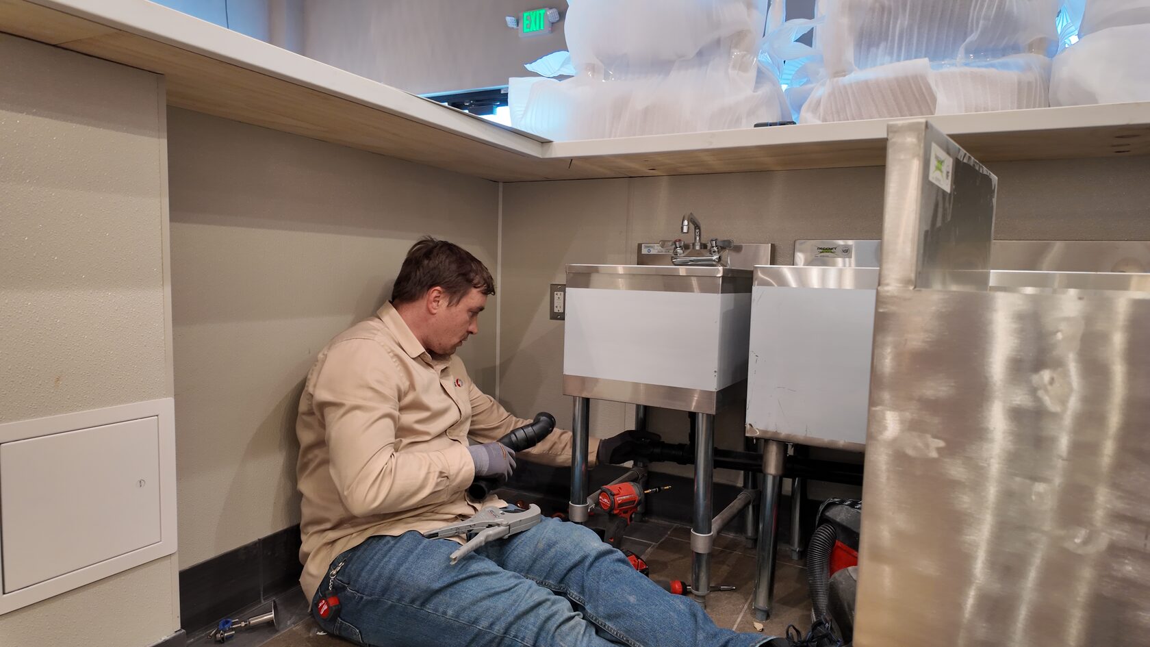 Plumber fixing sink with notes on bathroom drain installation mistakes to avoid