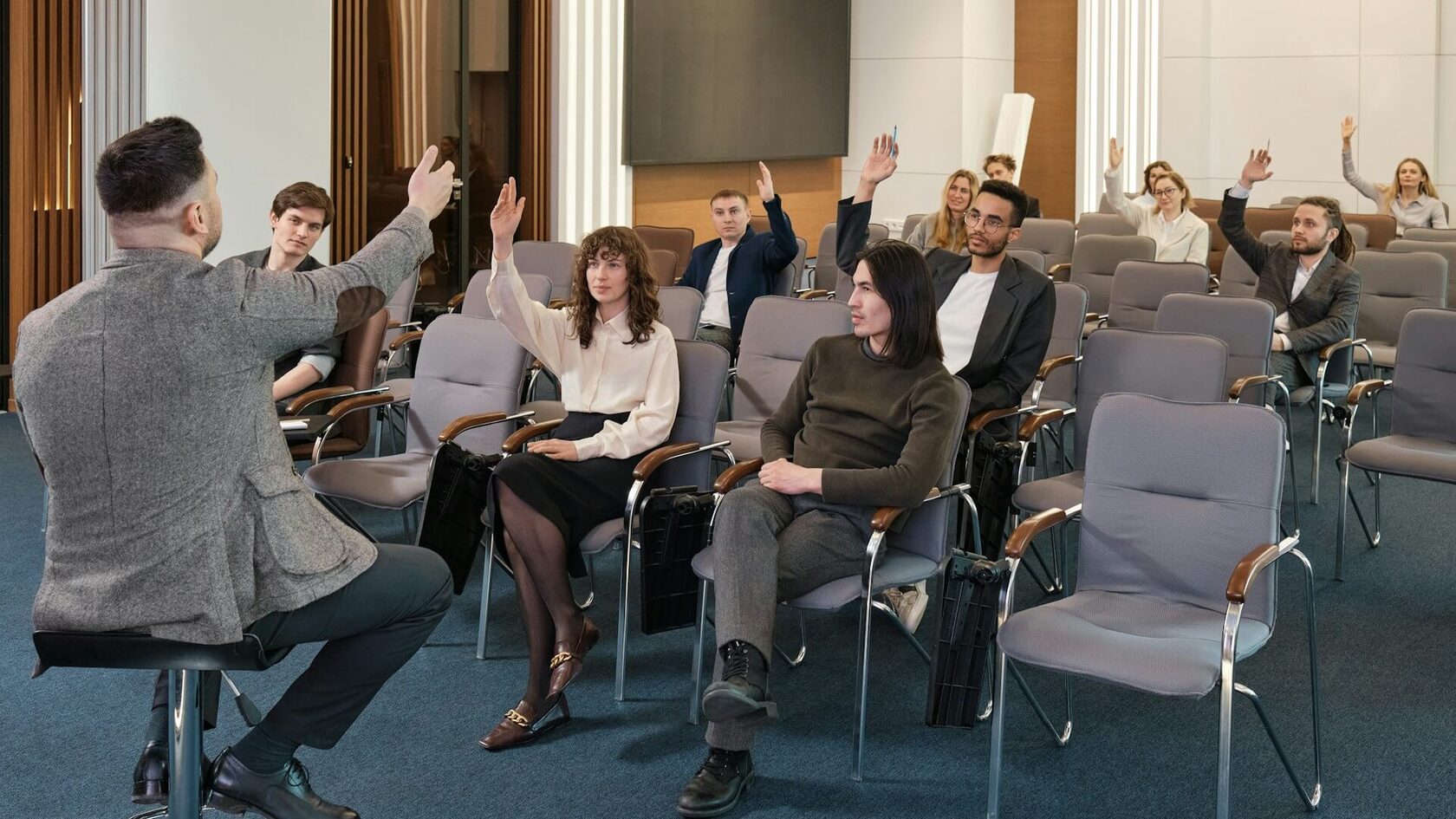 Группа студентов поднимает руки на занятии или семинаре