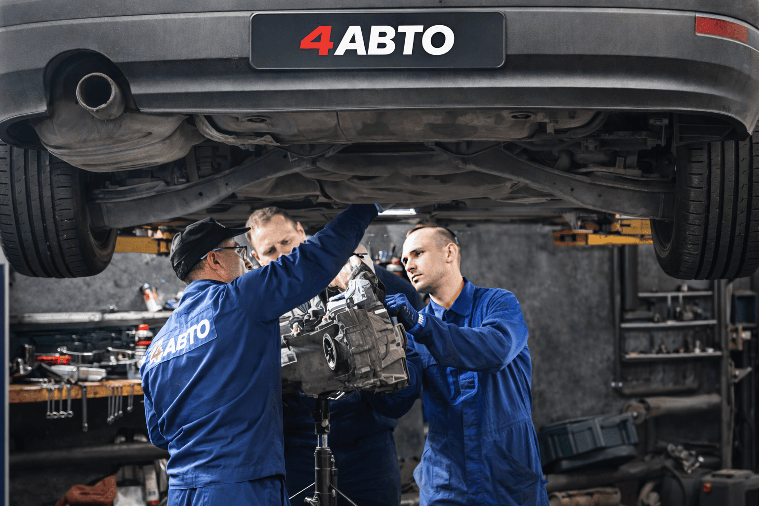 Механик на подъёмнике осматривает днище и подвеску автомобиля в рамках весеннего технического обслуживания