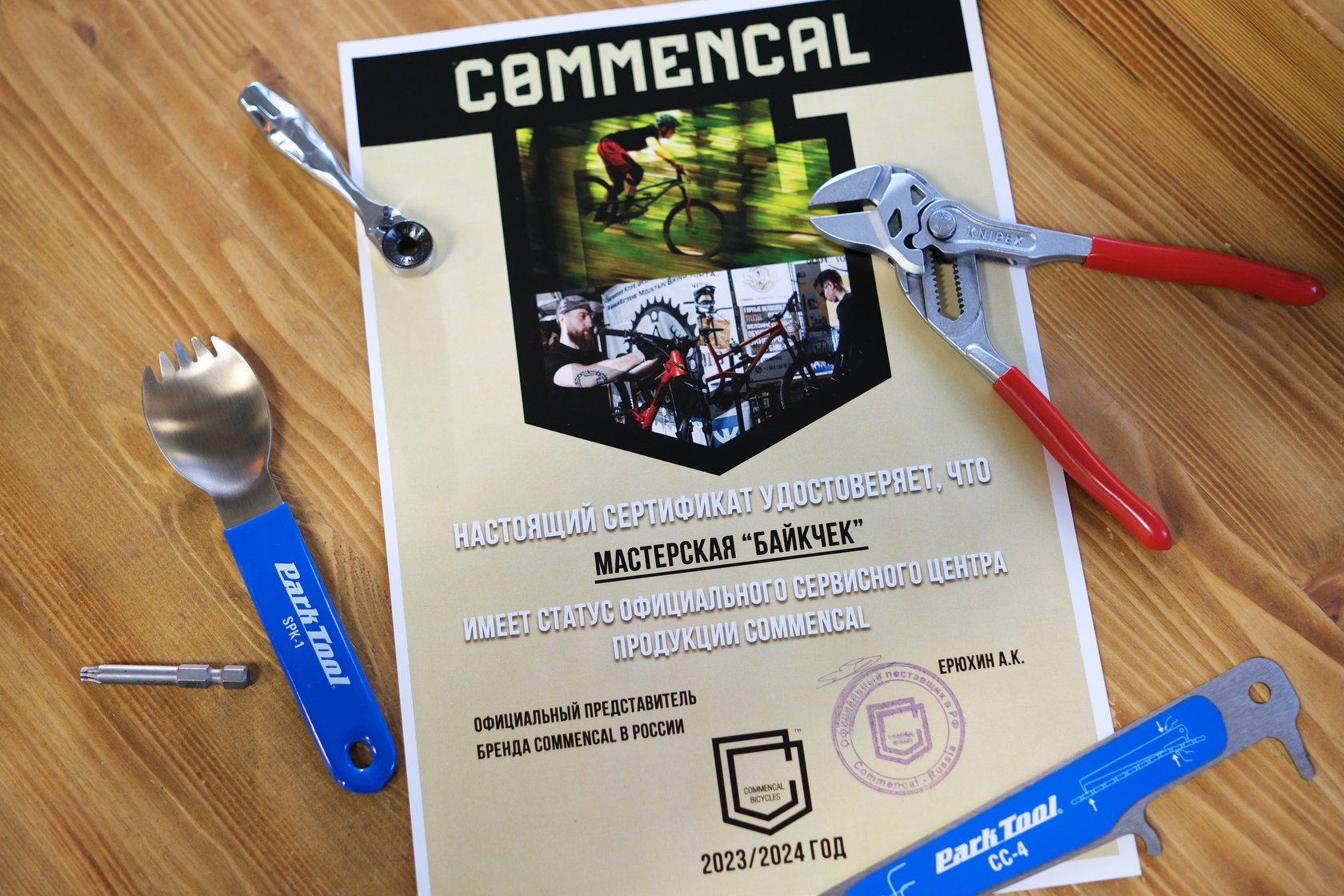 Сертификат официального сервисного центра Commencal мастерской Байкчек и инструменты на деревянном столе