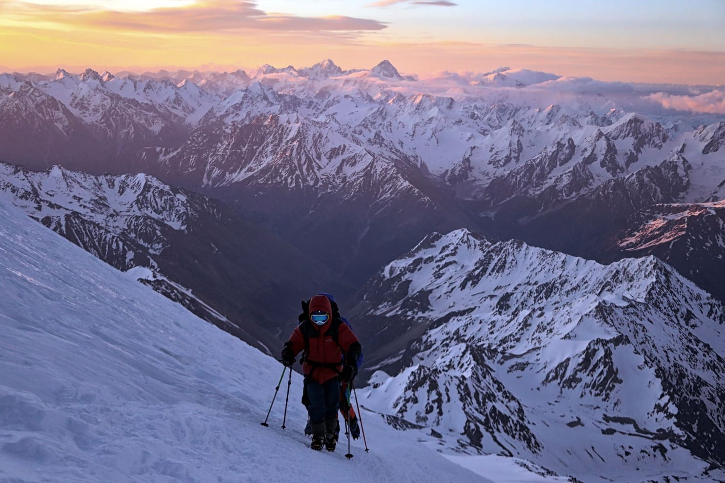 Lone climber on an Elbrus snow slope at sunrise above the Caucasus ridges