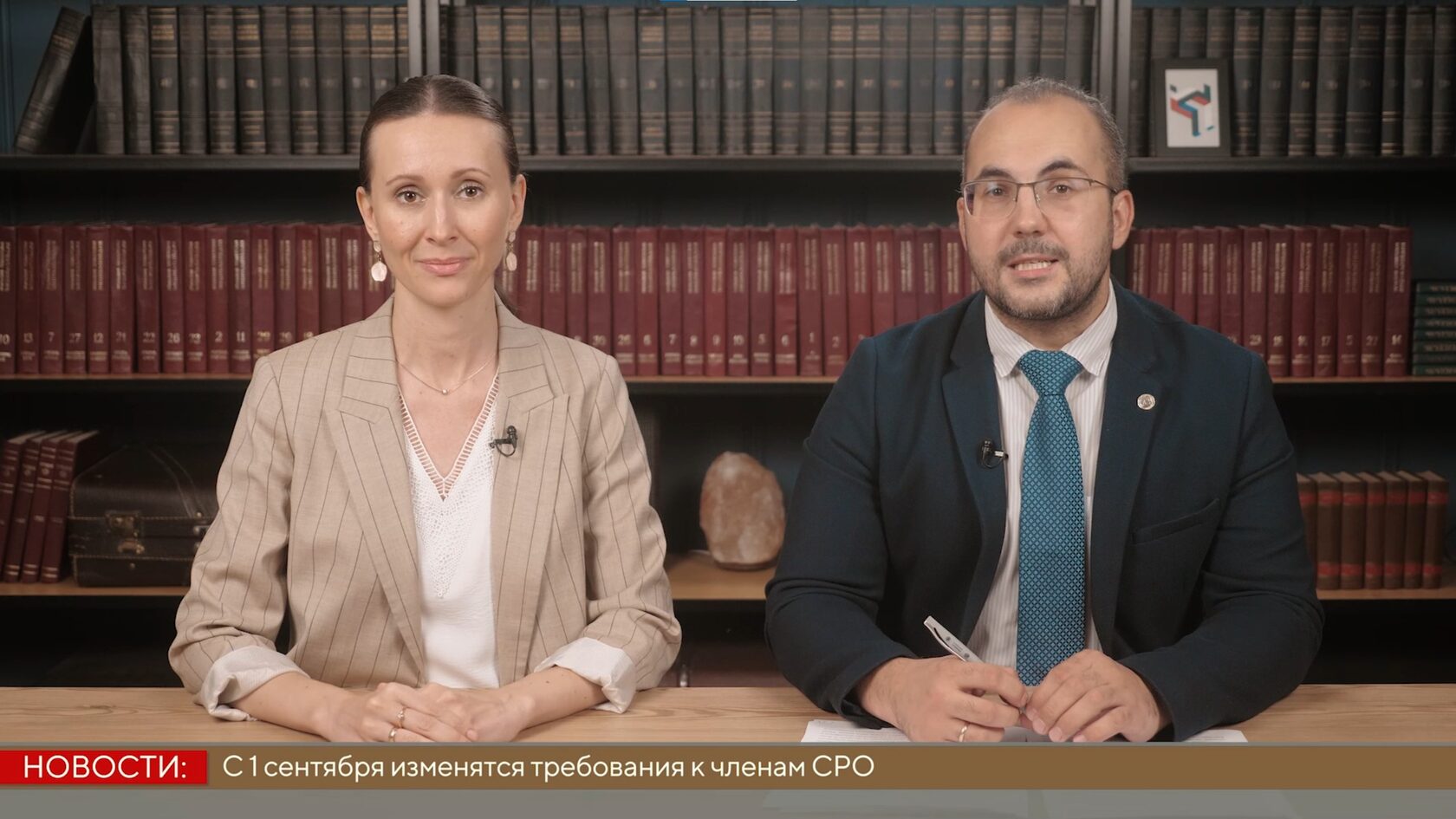 Мужчина и женщина ведут новостной выпуск за столом, внизу бегущая строка о требованиях к СРО