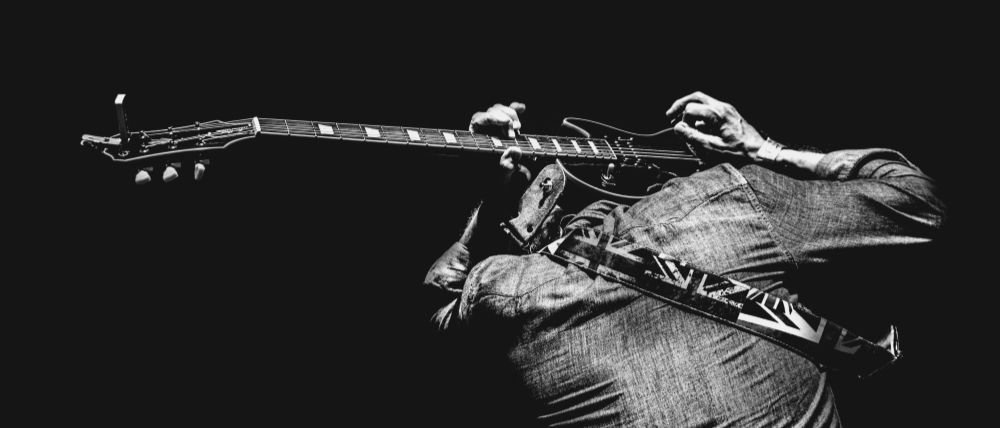Черное-белое изображение мужчины, демонстрирующего игру на электрогитаре