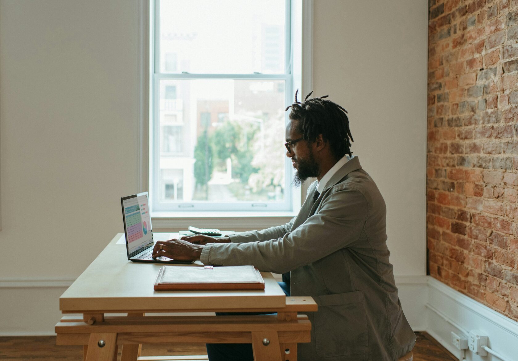 A man sitting at a desk, focused on his laptop, working diligently.