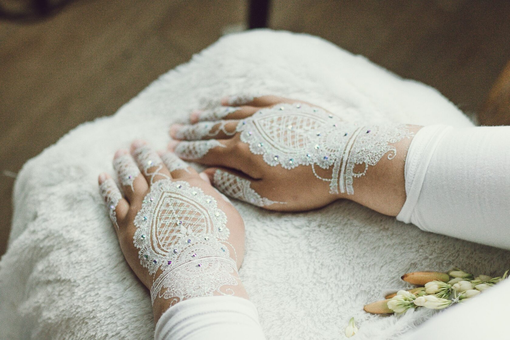 Delicate white lace-inspired body art on a shoulder