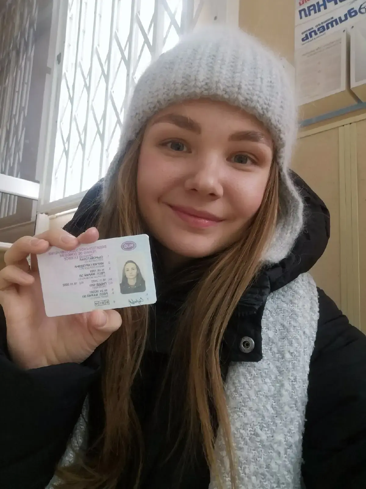 Выпускница показывает права, полученные после экзамена в ГИБДД
