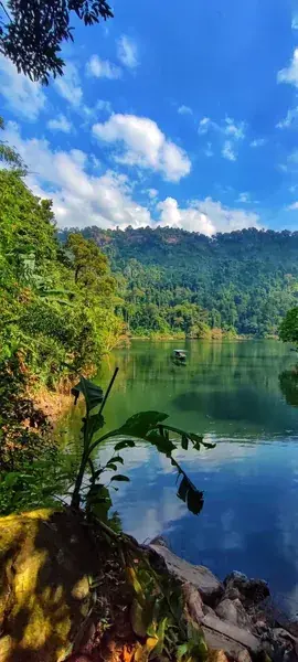 Лодка на водной глади у лесистых гор