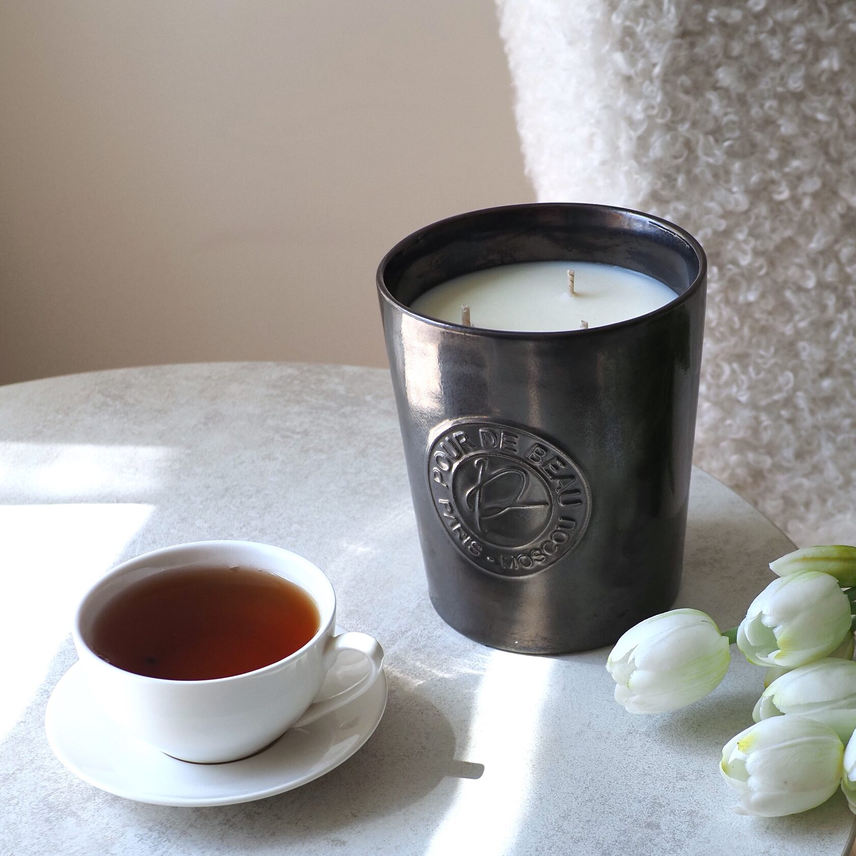 большая черная фарфоровая свеча на столе с чашкой чая