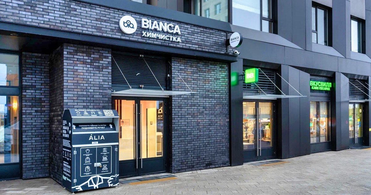 Вывеска химчистки BIANCA на тёмном фасаде торговой галереи жилого района ALIA