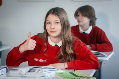 Ученица лицея «Квадриум» с учебником показывает большой палец вверх