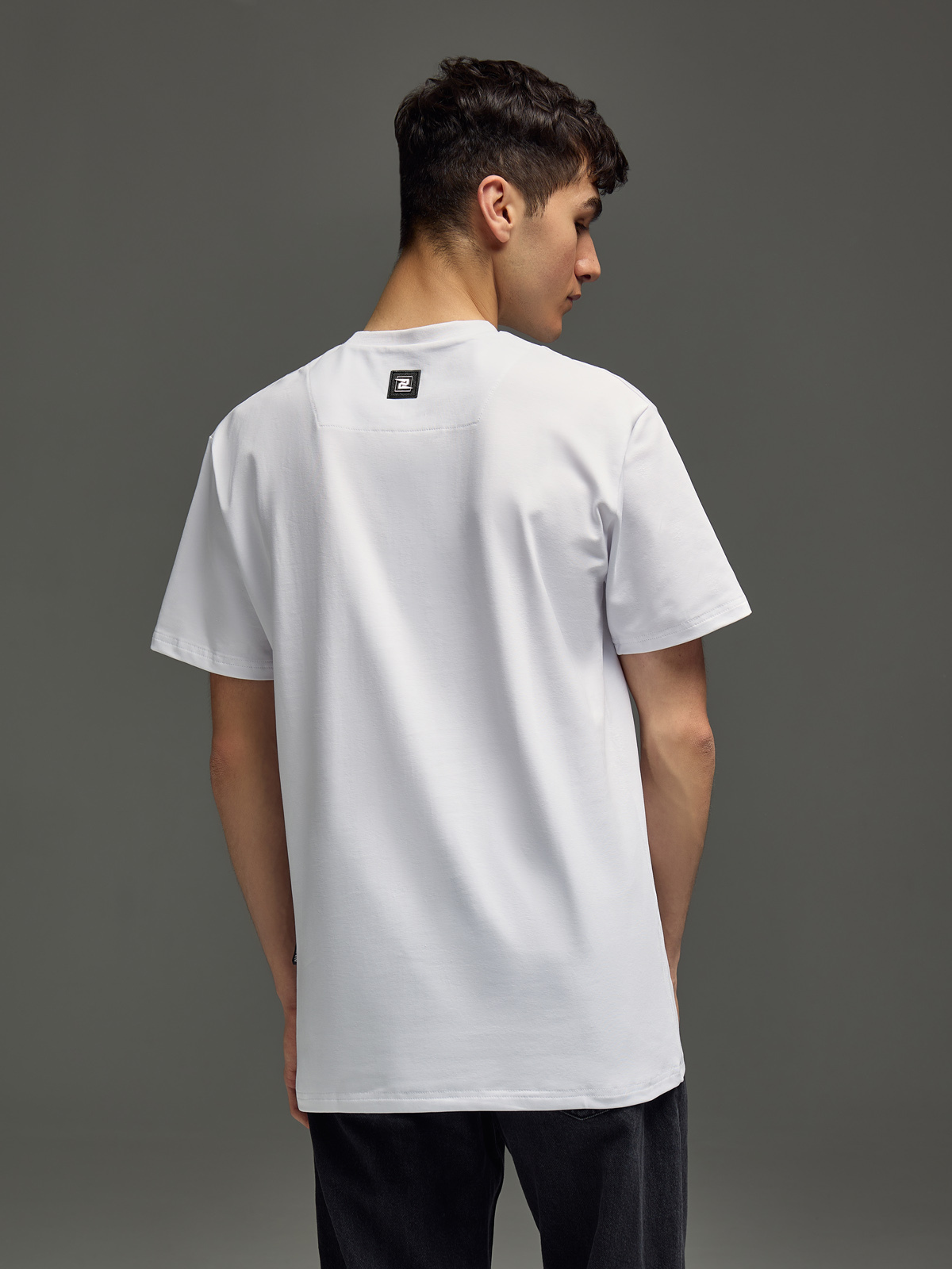 мужчина в футболке со спины на сером фоне