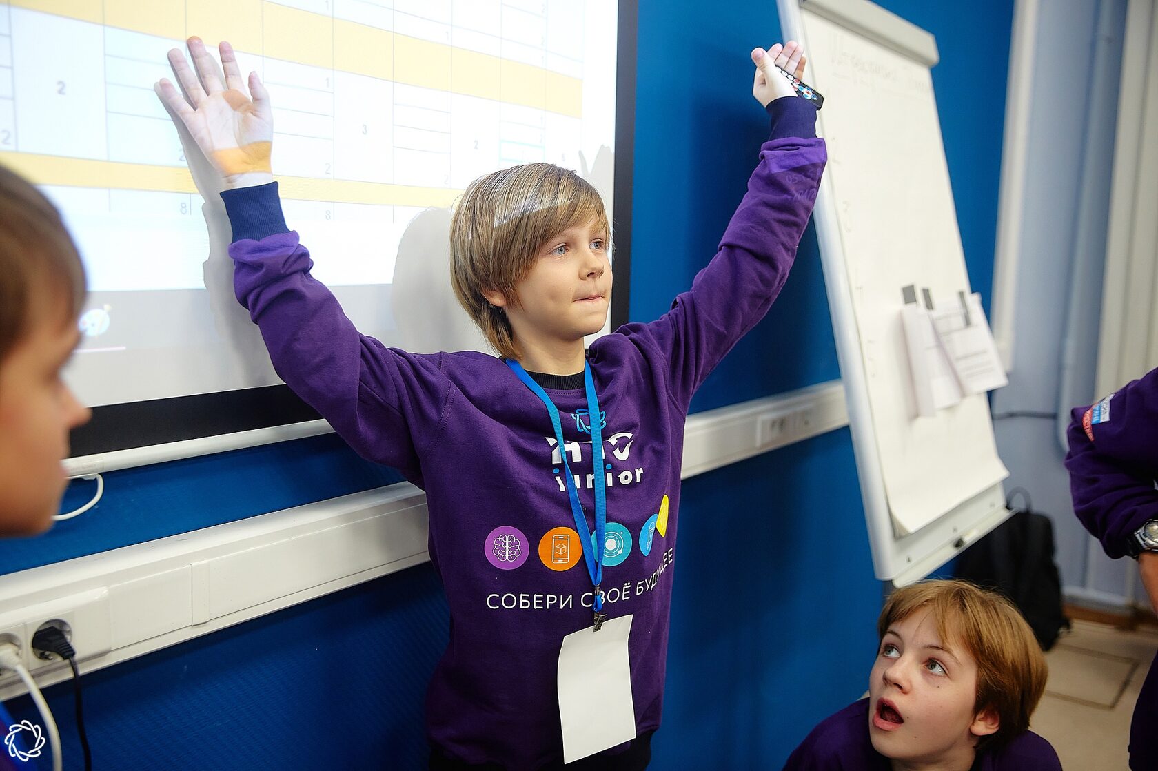 Финалист НТО Junior радостно вскидывает руки перед экраном с презентацией.