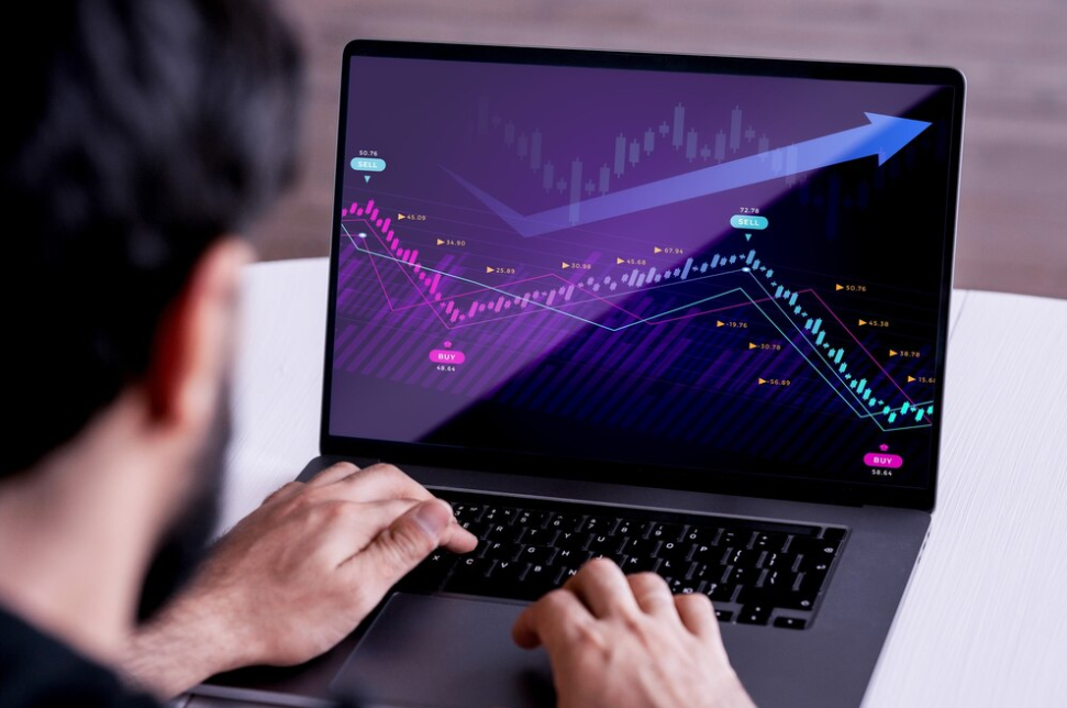 Active trading: Man in front of a laptop with price charts.