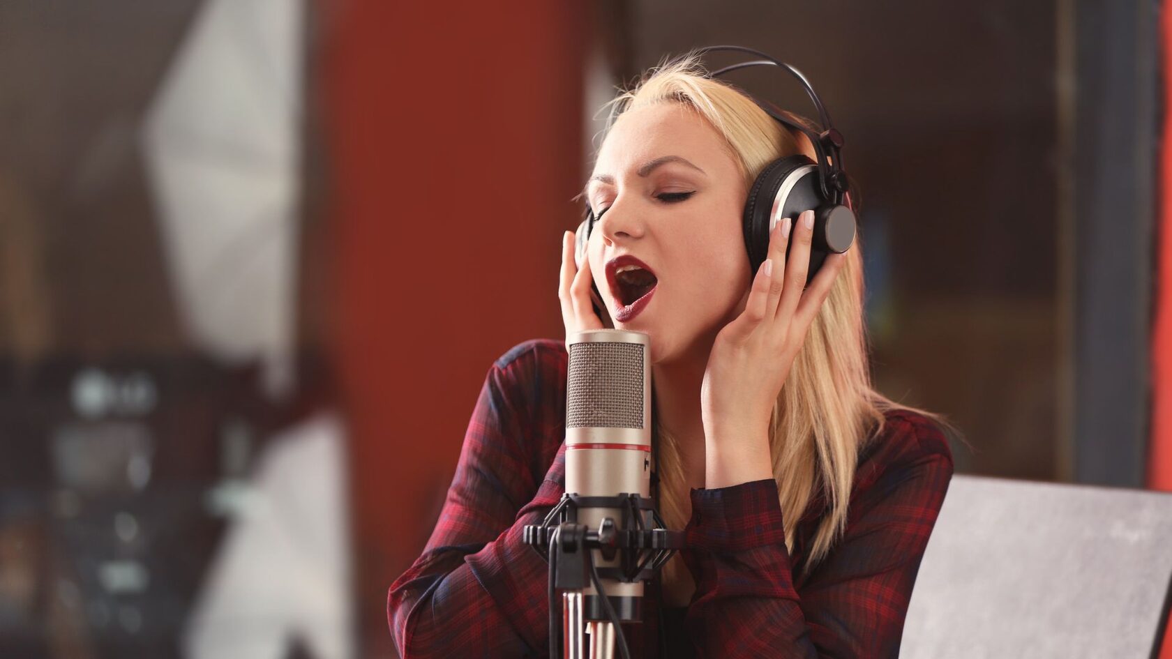 Профессиональная певица выполняет утренние распевки для вокала перед микрофоном, демонстрируя правильную технику дыхания и позицию корпуса для качественного пения