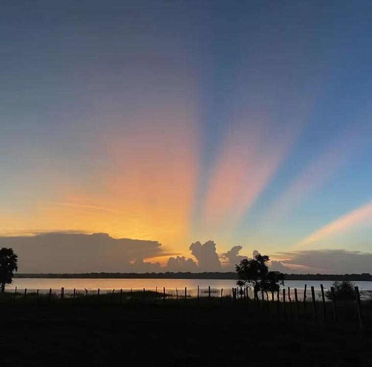 Crepuscular rays over the paddock and lake at dusk at Vonfidel Ranch