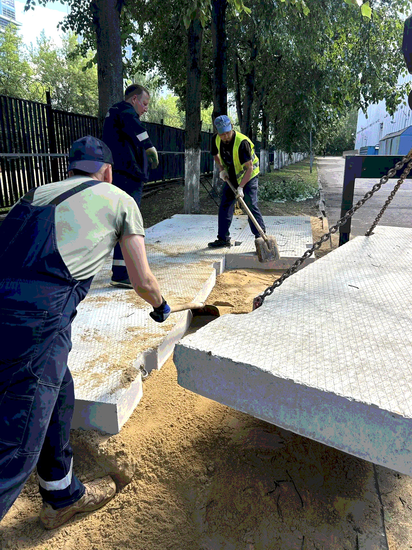 Укладка железобетонных плит на песчаную подушку для строительства ровной площадки.