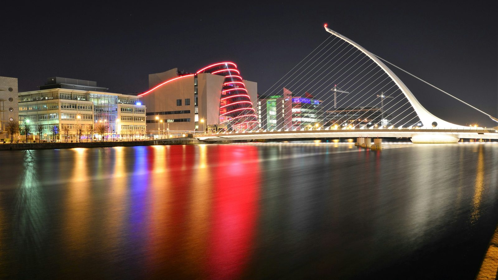 The Samuel Beckett Bridge and the Convention Centre Dublin lit up at night, reflected in the River Liffey in the Docklands