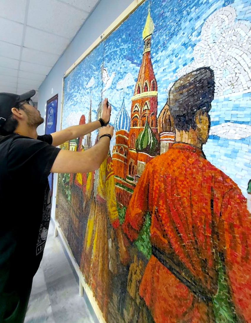 Мастер устанавливает верхний фрагмент панно с башней Кремля