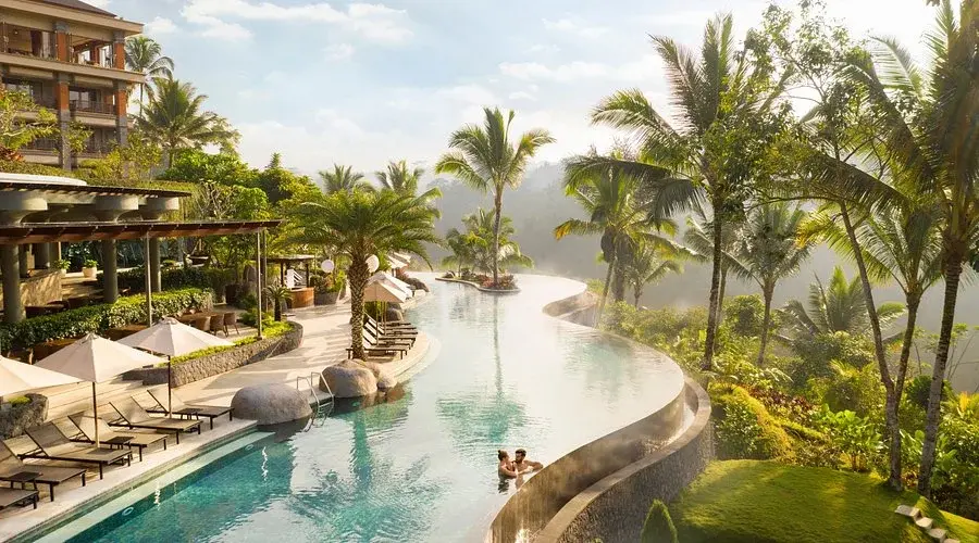 A couple relaxing in the spectacular winding infinity pool overlooking the dense tropical forest at Padma Resort Ubud.