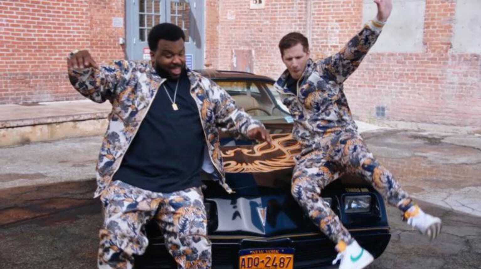 Brooklyn 9-9: Jake and Doug Judy wearing matching camo track suits near a Pontiac Firebird.