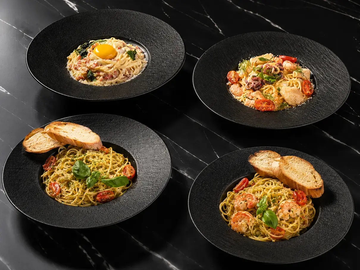A sleek black table showcasing four delicious spaghetti dishes from Eden Hookah Club's menu, including Carbonara and Seafood options, perfect for a late-night feast when you're looking for the best pasta in Seminyak.
