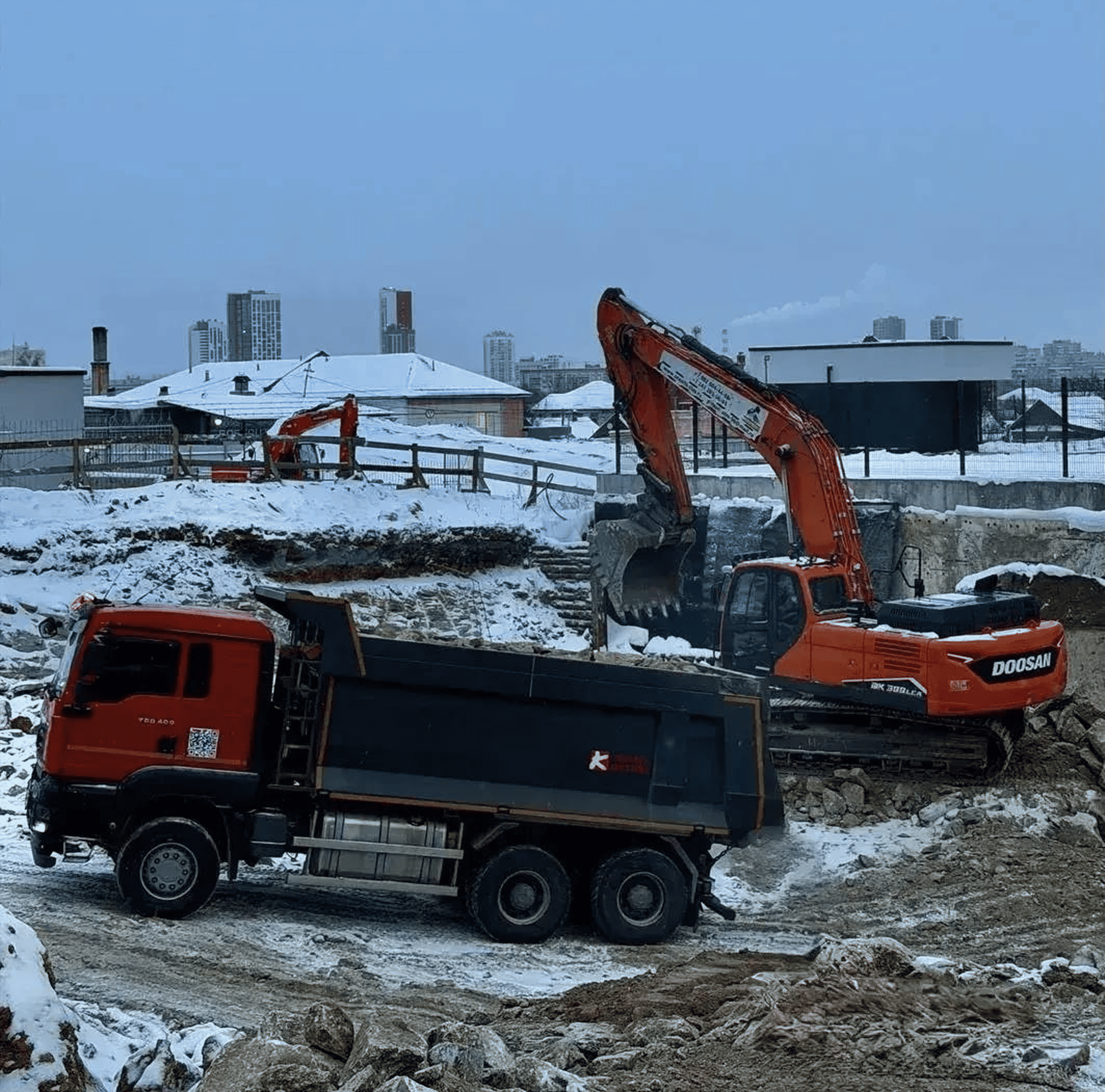 Самосвал и экскаватор Doosan на зимней стройплощадке — спецтехника в аренду