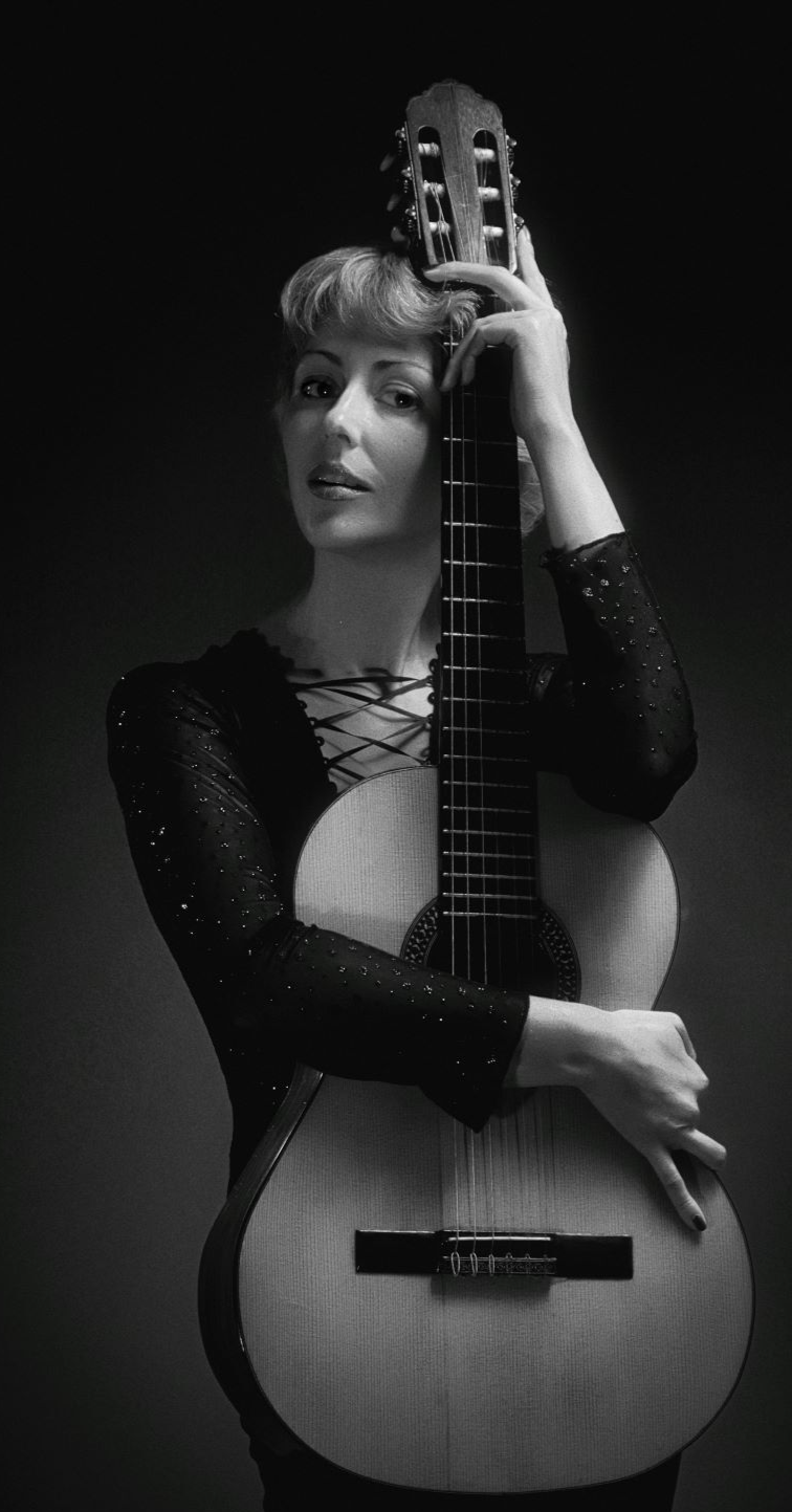 Черное-белое изображение девушки, демонстрирующей классическую гитару
