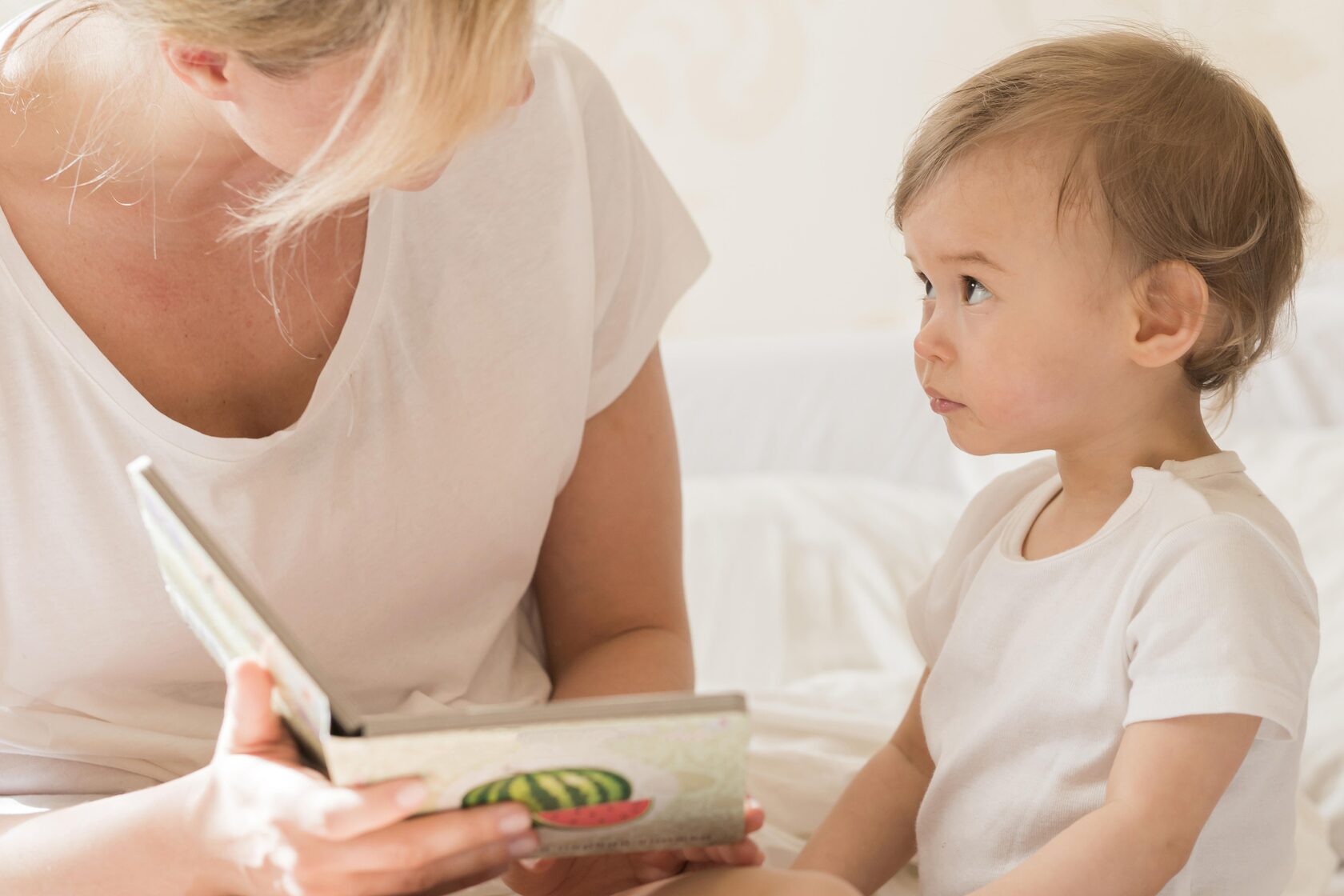 Mother reading a picture book to baby as a sleeping ritual before bed to support early language development.