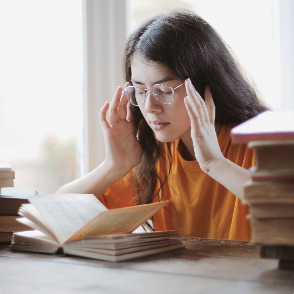 Девочка в очках читает книгу за столом
