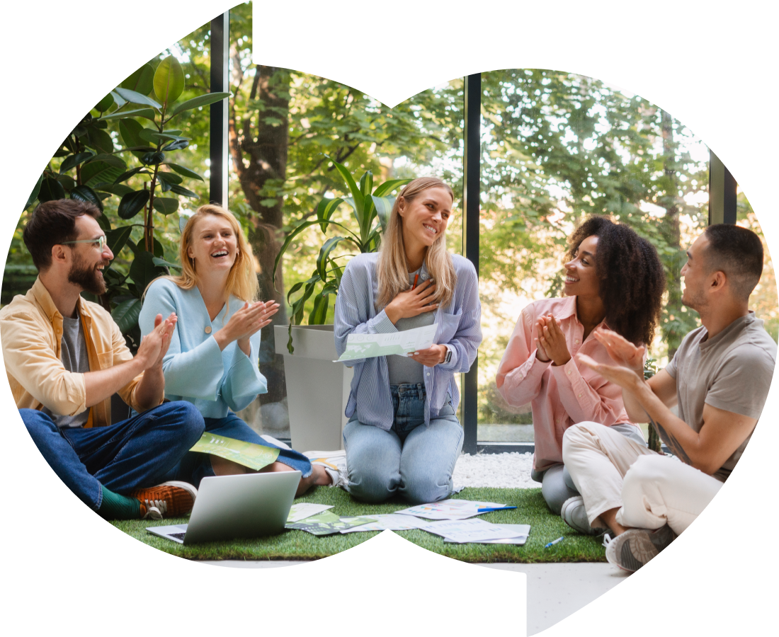 Group of friends sitting on the floor in a circle, laughing and applauding.